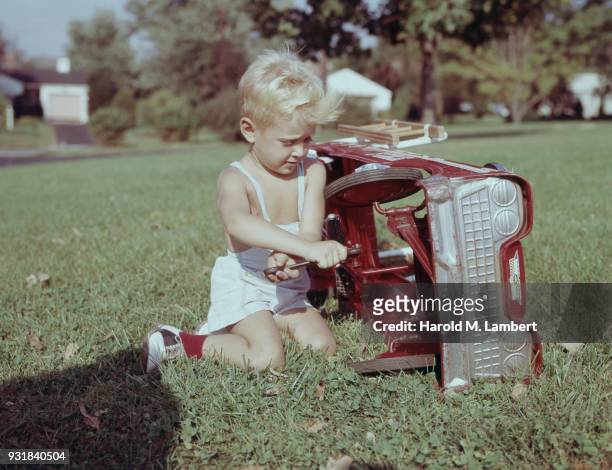 Boy repairing toy car on grass