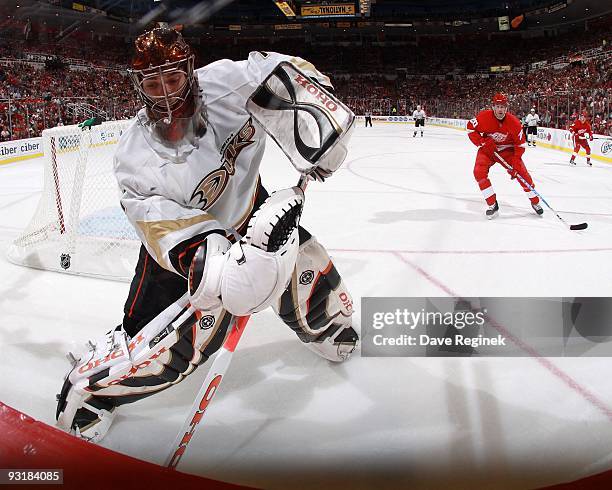 Jonas Hiller of the Anaheim Ducks stops the puck behind the net as Drew Miller of the Detroit Red Wings closes in during a NHL game at Joe Louis...