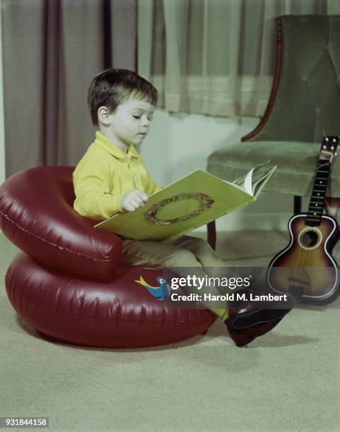 Boy reading book while sitting on inflatable chair