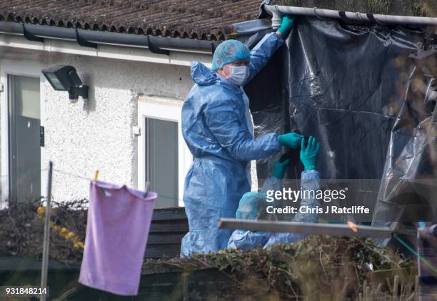 Police forensics officers erect a tarpaulin sheet over the rear of the home of Russian exile Nikolai Glushkov who was found dead at his home in New...