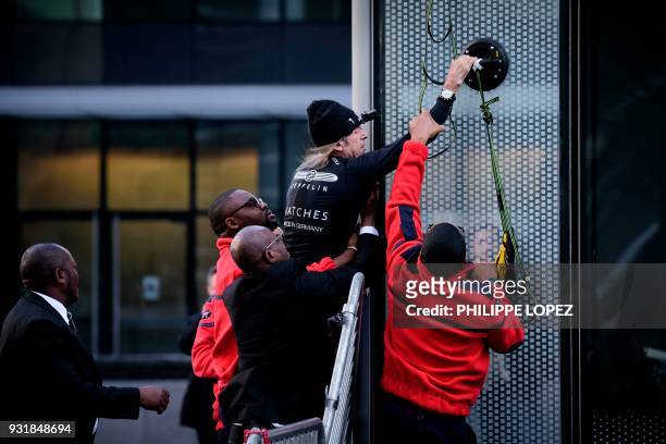 Alain Robert, the French urban climber dubbed Spiderman, is grabbed by security guards preventing him to climb a building hosting the headquarters of...