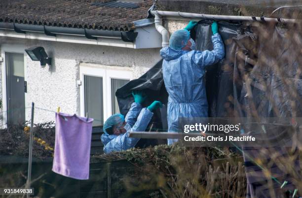 Police forensics officers erect a tarpaulin sheet over the rear of the home of Russian exile Nikolai Glushkov who was found dead at his home in New...