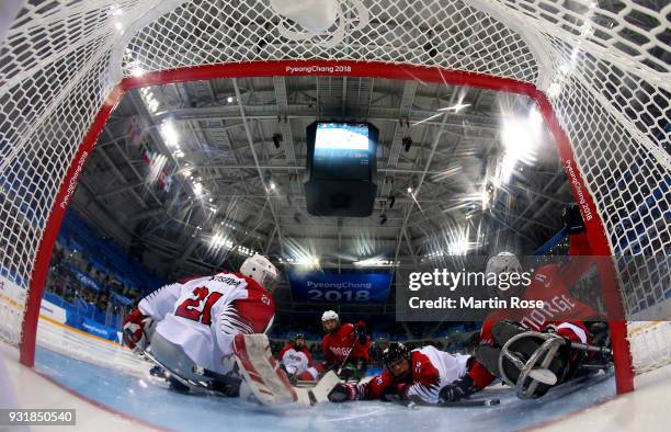 Knut Andre Nordstoga of Norway scores a goal over Shinobu Fukushima, goaltender of Japan in the Ice Hockey Classification game between Norway and...