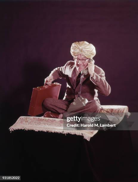 Man with genie hat talking on phone while sitting on magic carpet