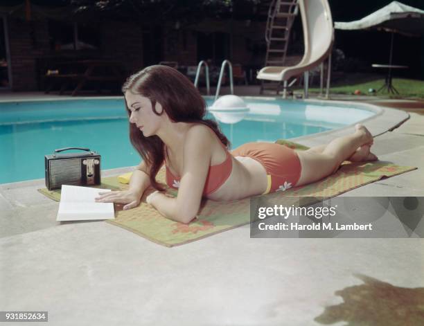 Young woman reading book near pool
