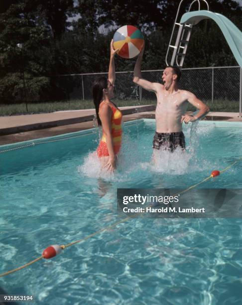 Young couple playing with beach ball in swimming pool