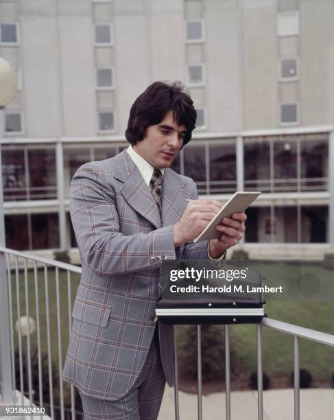 Businessman standing out side office and writing on notepad