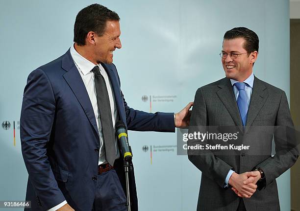 Actor Ralf Moeller gestures towards German Minister of Defense Karl Theodor zu Guttenberg as the two adress the media during a short press conference...