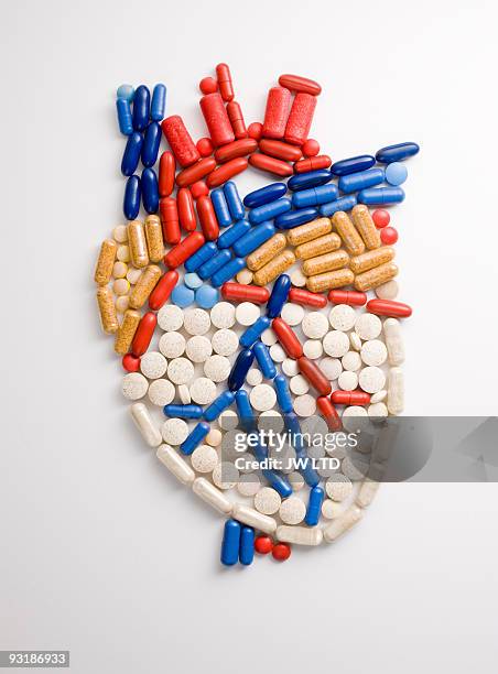 capsules and pills in shape of human heart - heart pill stock-fotos und bilder
