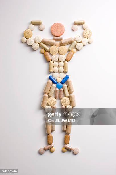 vitamin pills in shape of man flexing muscles - menselijke vorm stockfoto's en -beelden