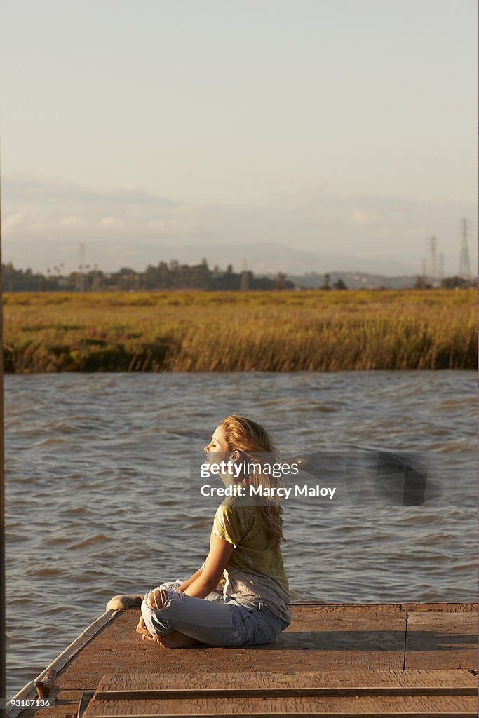 Young woman sitting crosslegged on dock