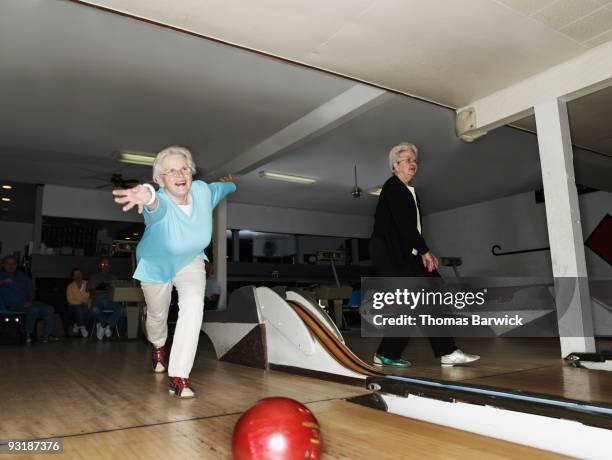 mature woman throwing bowling ball down lane - ten pin bowling foto e immagini stock