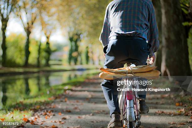 frenchman on bike with baguettes - barra de pan francés fotografías e imágenes de stock