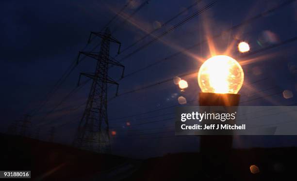 In this photo illustration an incandescent light bulb is illuminated next to electricity pylons on November 18, 2009 in Greenock, Scotland. As world...