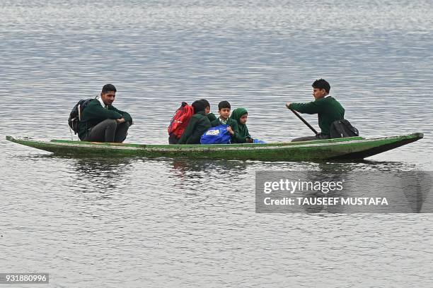 Kashmiri school children row their boat on Dal lake as they return home after school during a cold and rainy day in Srinagar on March 14, 2018 / AFP...