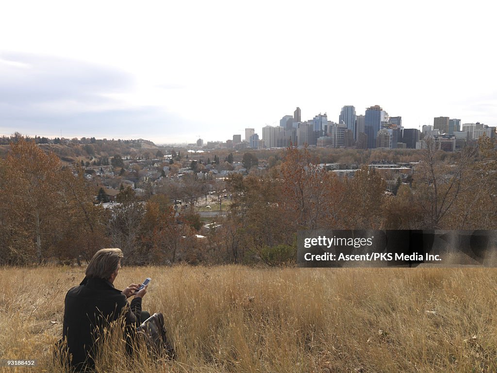 Businessman sends text message on hill above city