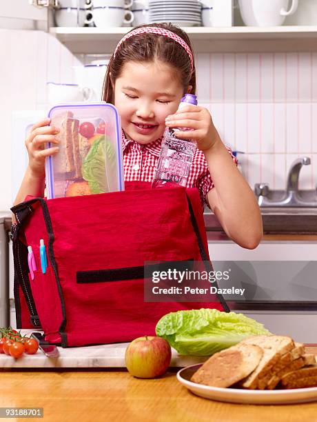 school girl packing lunchbox in school bag. - satchel bag stock-fotos und bilder