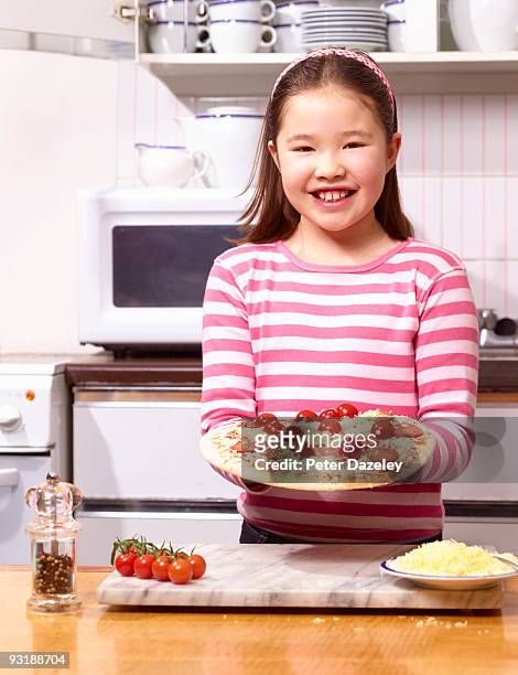9 year old girl with homemade pizza in kitchen. - old person kitchen food ストックフォトと画像