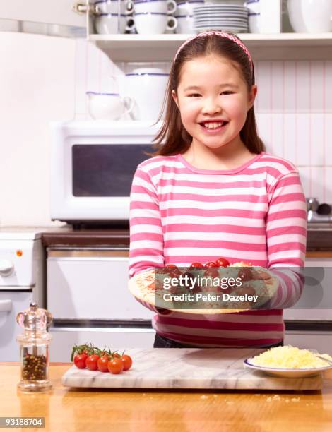 9 year old girl with homemade pizza in kitchen. - parsons green stockfoto's en -beelden