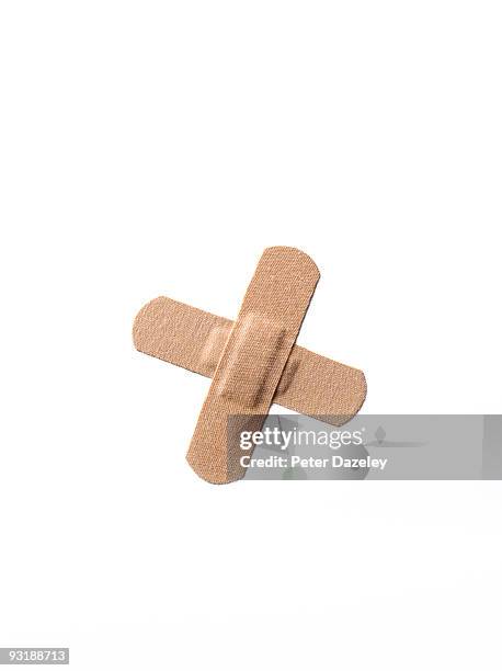 a stack of two adhesive plasters in shape of an x. - bandage imagens e fotografias de stock