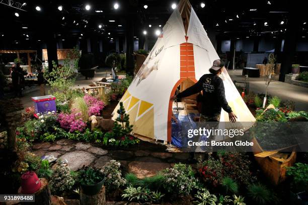 Anthony Vargas, of North Andover, stretches out his arms as he works on an exhibit by Samantha's Garden called Backyard Family Retreat at The Boston...