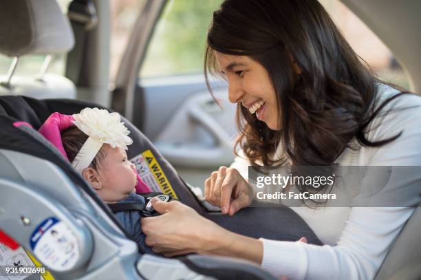 mom buckling infant into car seat - cadeirinha imagens e fotografias de stock