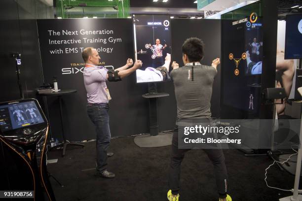 An attendee demonstrates the SixPad interactive training gym at the South By Southwest conference in Austin, Texas, U.S., on Tuesday, March 13, 2018....