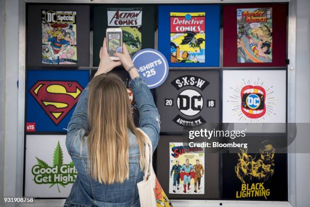 An attendee takes a photograph of DC comic book themed shirts for sale at the South By Southwest conference in Austin, Texas, U.S., on Tuesday, March...