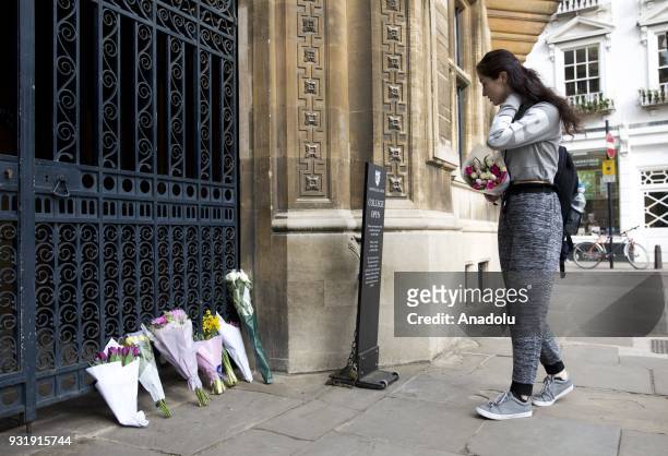 Girl brings flowers to the gate of Gonville and Caius College in Cambridge, United Kingdom to pay tribute to world renowned physicist Stephen Hawking...