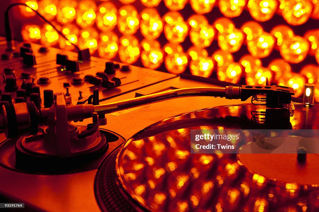 A turntable and sound mixer illuminated by lighting equipment