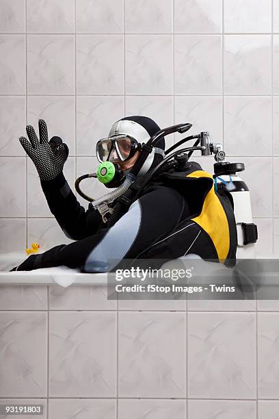 a scuba diver sitting in a bubble bath giving the ok sign - eccentrico foto e immagini stock