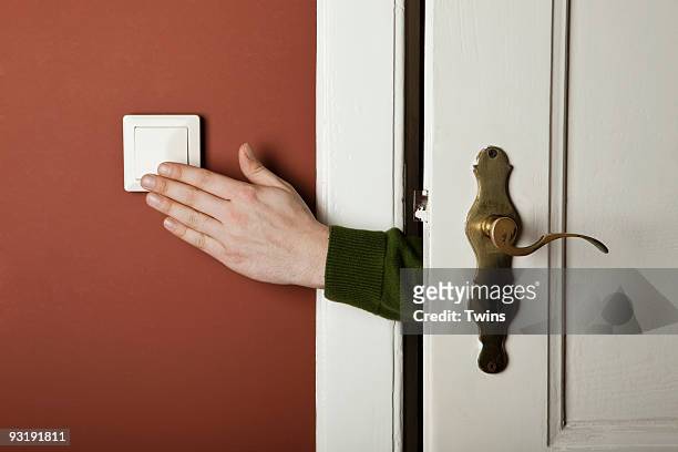 a hand turning off a light switch - turning on or off stock-fotos und bilder