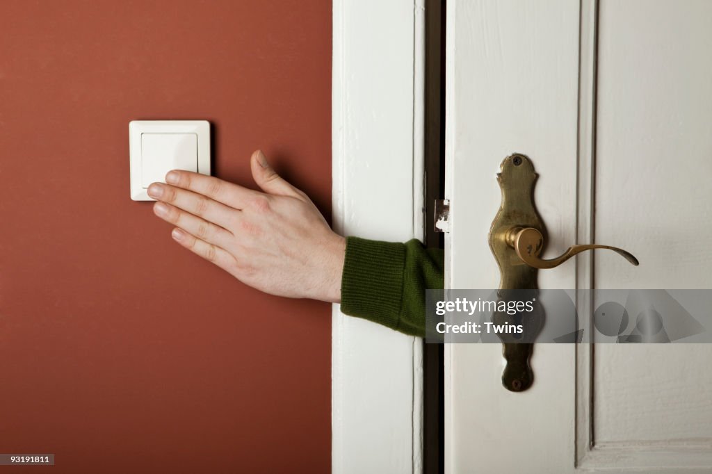 A hand turning off a light switch