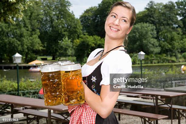 a traditionally clothed german woman serving beer in a beer garden - biergarten stock-fotos und bilder