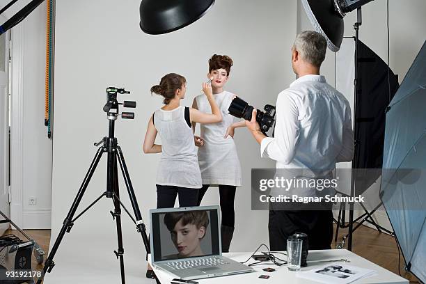 a photographer, model and make-up artist on set of a fashion shoot - tripod lamp stock pictures, royalty-free photos & images