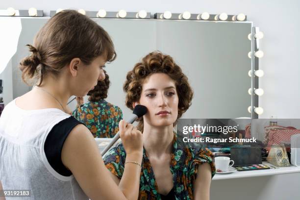 a make-up artist applying make-up on a model - künstlergarderobe stock-fotos und bilder