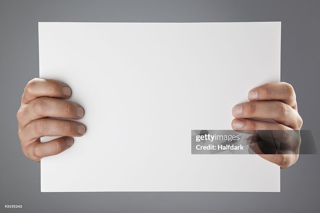 Hands holding up a white piece of paper