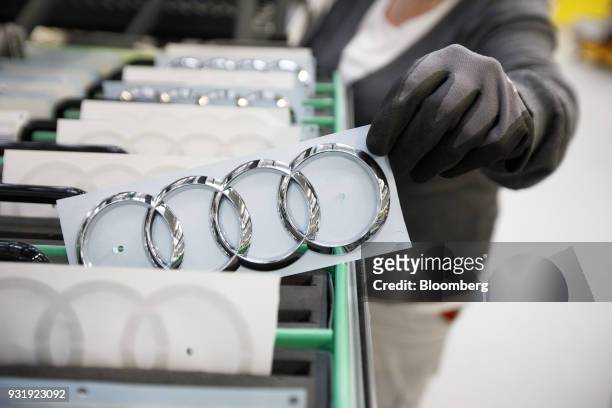An employee picks a Audi AG rings logo badge for fitting to an automobile inside the Audi AG headquarter factory in Ingolstadt, Germany, on...
