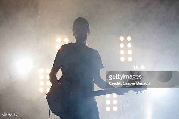 a rock musician playing a guitar on a stage - popmuzikant stockfoto's en -beelden