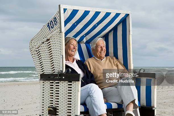 a senior couple sitting together in a hooded beach chair - hooded beach chair stock pictures, royalty-free photos & images