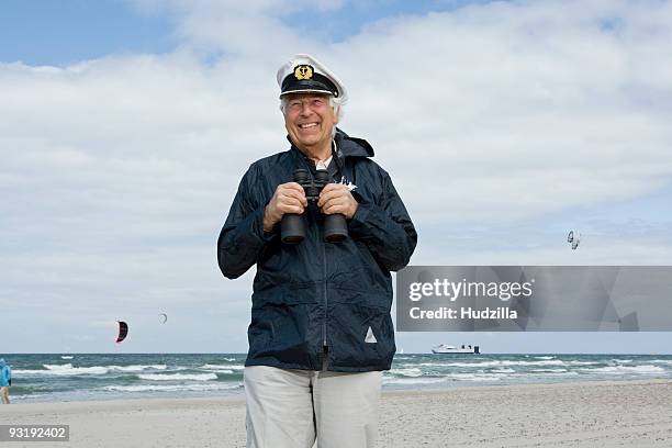 a senior man on a beach holding binoculars - sailor hat stock pictures, royalty-free photos & images
