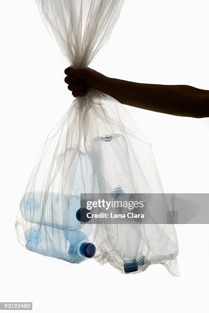 a human hand holding a transparent garbage bag of plastic bottles - transparent bag stock pictures, royalty-free photos & images