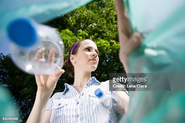 a woman throwing a plastic bottle away - altglasbehälter stock-fotos und bilder