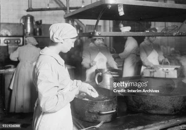 View of cooks as they make doughnuts in the Central Diet Kitchen in the basement of the American Red Cross Headquarters, Paris, France, October 1918....