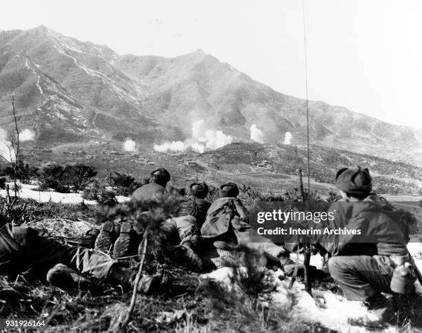 View of American soldiers from the 35th Infantry Regiment as they crouch down and observe white phosphorous shells was they explode on enemy...