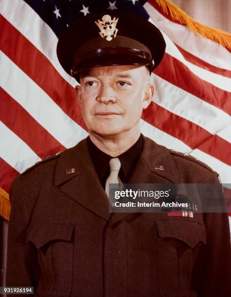 Portrait of American military commander General Dwight D Eisenhower as he stands in front of an American flag, 1943.