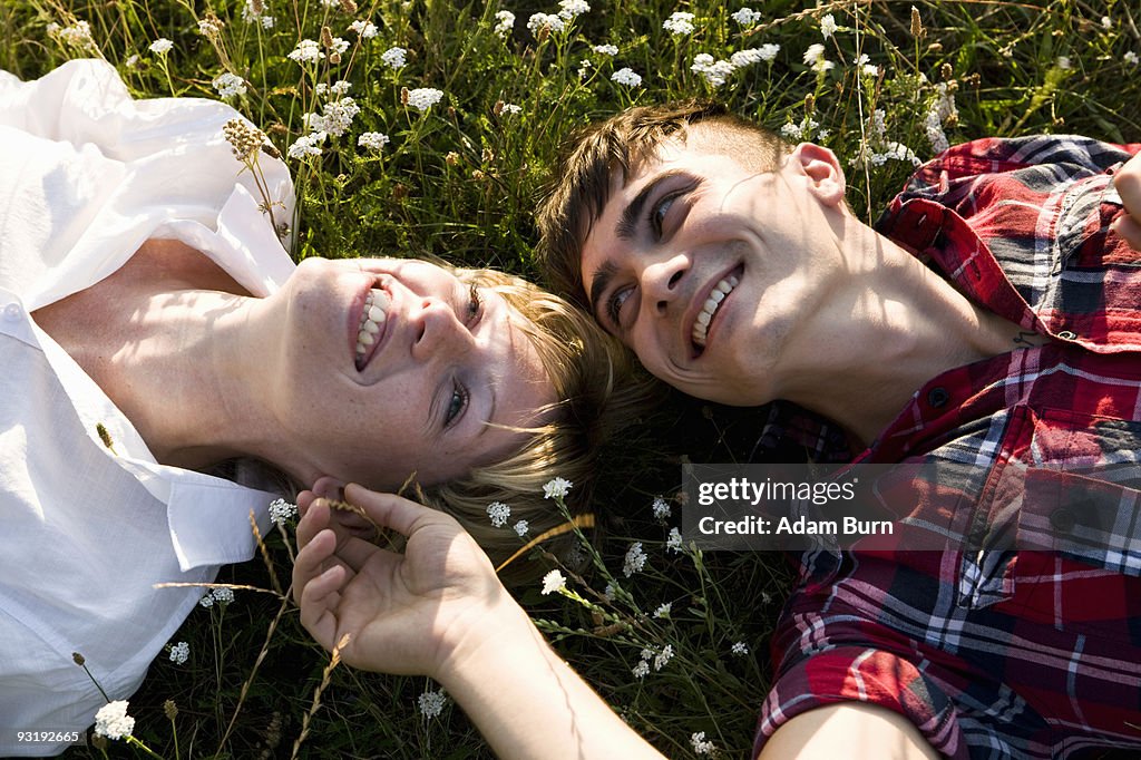 A young couple lying in on their backs in grass, close-up