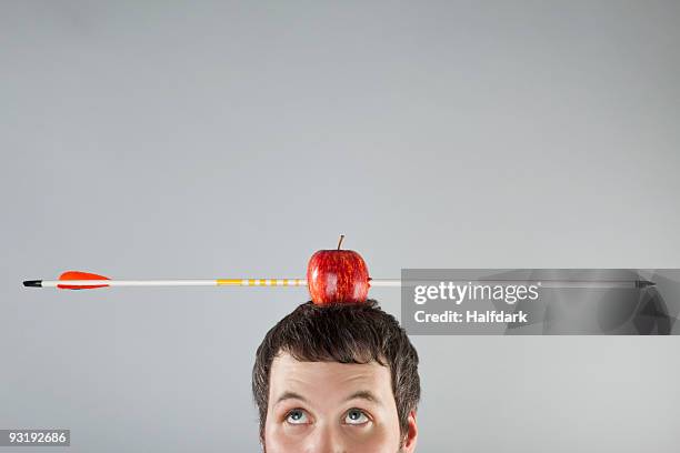 a man with an apple on top of his head and an arrow piercing it - bow and arrow stock pictures, royalty-free photos & images