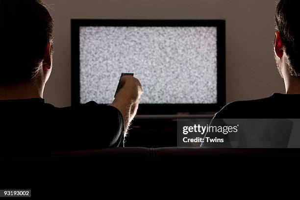 two men watching static on television - parasitage photos et images de collection