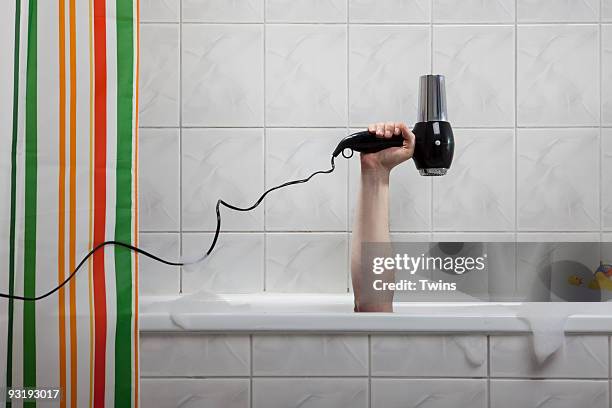 a human hand sticking out of a bathtub holding a hairdryer - bad body language stockfoto's en -beelden
